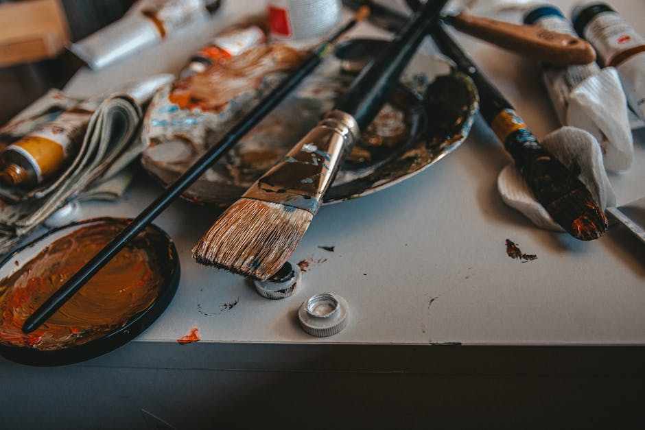 A cluttered artist's workspace with paintbrushes and palette, showcasing creativity.