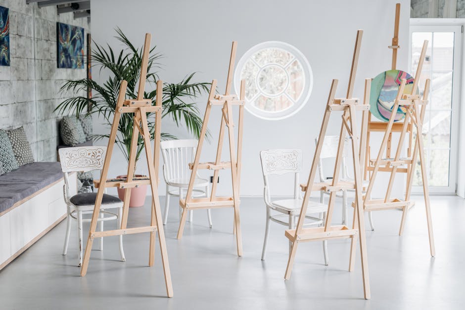 A sunlit art studio featuring wooden easels and chairs, perfect for workshops.